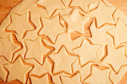 the process of making christmas cookies, raw dough, rolling pin and baking star forms.