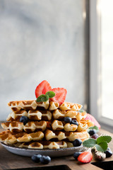 Belgian waffles with strawberries, blueberries, homemade healthy breakfast, toned image, selective focus