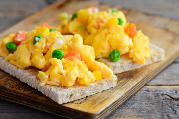 Scrambled eggs omelette. Homemade scrambled eggs omelette with vegetables on crispy bread toasts. Healthy eating. Rustic style. Closeup