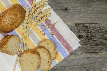 Buns, grains and ears of wheat on a wooden table