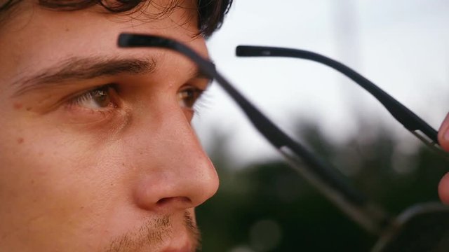 Handsome young fashion man wearing sunglasses and looks sunset on the beach. slow motion. 1920x1080