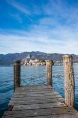 Fototapeta premium Wooden dock on Lake Orta, opposite the island of San Giulio island with a Benedictine nunnery monastery