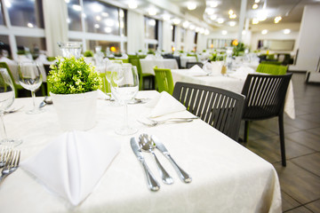 Beautifully organized event - served festive white tables ready for guests. Event in a restaurant. Banquet, wedding decor, celebration. 