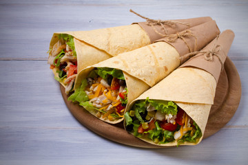 Chicken wraps. Tortilla, burritos, sandwiches twisted rolls on wooden table