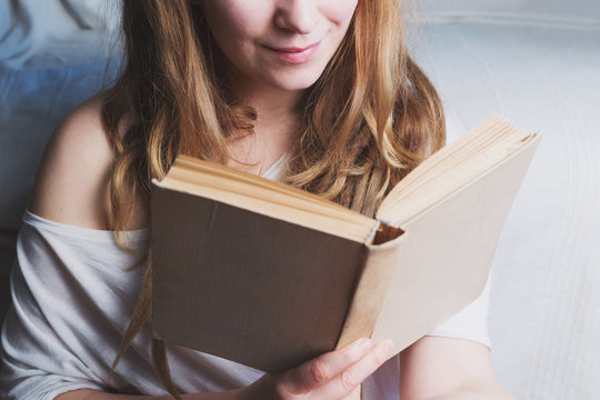 Woman with ginger dreadlocks is reading a book