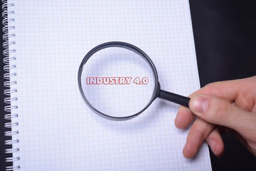 Businessman looking at a magnifying glass word:INDUSTRY 4.0