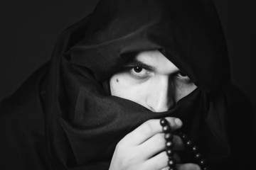 Naklejka premium Portrait of person in scarf holding beads