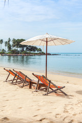 Lounge chairs under umbrella on beach.