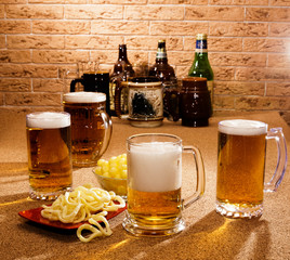 Glasses of beer and plates of appetizers are on the table.