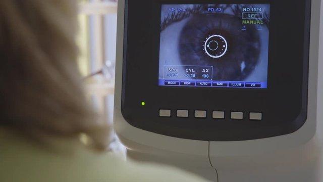 An optician looking at a big screen which is showing an eye