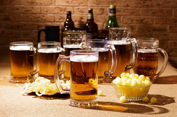 Glasses of beer and plates of appetizers are on the table.