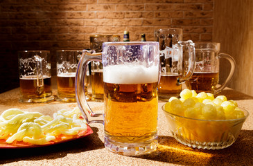 Glasses of beer and plates of appetizers are on the table.
