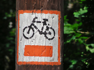 Orange painted bicycle trail sign on the tree