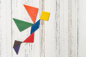 wooden tangram shaped like a flying angel on white with copy space