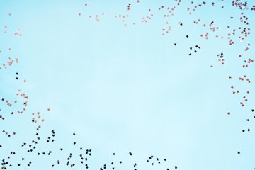 Star shaped silver sequins over blue background. Copy space.