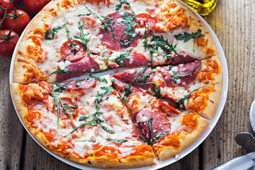 Stone baked pizza with salami, pepperoni and rucola 