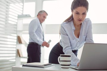 Focused on work. Nice beautiful attractive woman looking at the laptop screen and focusing on work while being photographed