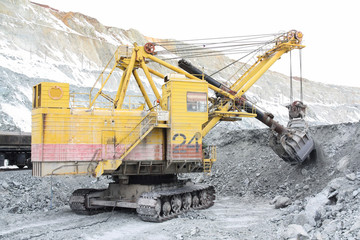 The excavator loads the stones into the cars. Loading ore into the railway cars in the quarry.