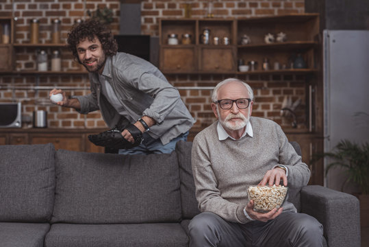 Adult Son And Senior Father Watching Baseball Game At Home