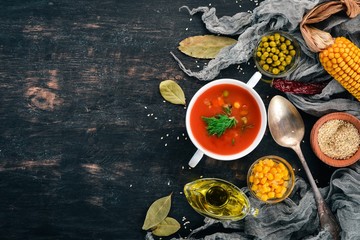 Tomato soup with chili and vegetables. Healthy food. On a black wooden background. Top view. Copy space for your text.