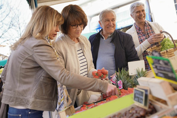 Senior people at the farmer's fresh market buying fruits and vegetables