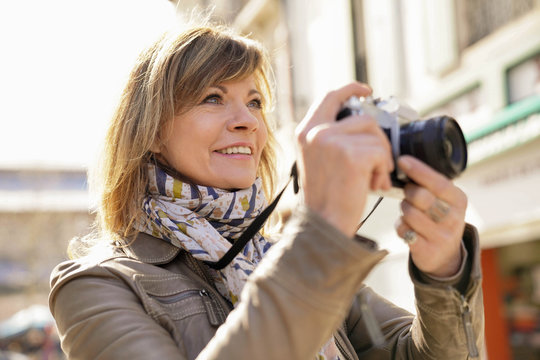 Mature woman photographer taking pictures in town