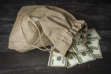 A full bag of dollars on a dark table