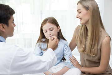 Obraz premium Male doctor examining inside girl mouth in clinic. People with health care and medical concept