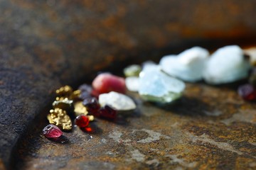 Uncut gemstones and nuggets of gold from Lapland, displayed on a rusty gold pan