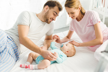 Young parents touching infant daughter in bed