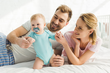 Smiling parents holding infant daughter with baby dummy