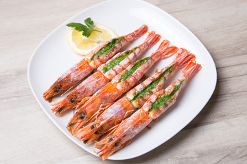 Baked langoustines on a white plate. Selective focus, close-up.