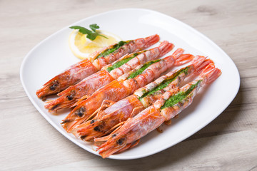Baked langoustines on a white plate. Selective focus, close-up.
