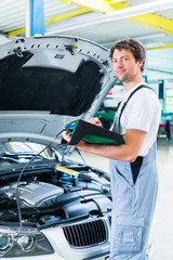 Car mechanic with diagnostic tool in car workshop