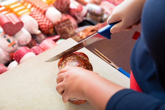 Frau in Fleischerei schneidet Chorizo Wurst