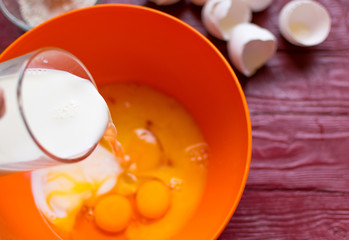 Adding milk to the eggs for whipping.