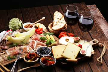 Italian antipasti wine snacks set. Cheese variety, Mediterranean olives, pickles, Prosciutto di Parma with melon, salami.