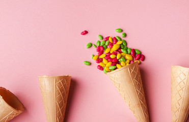 Waffle cones and sprinkles on pink surface