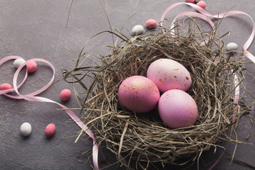 Easter background. Colored eggs in nest on gray stone surface