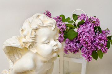 romantic still life of lilac blossom and angel sculpture on white