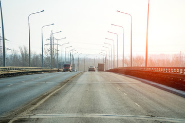 Public road roadway for transport in sunlight. Along the edges of the road, lampposts