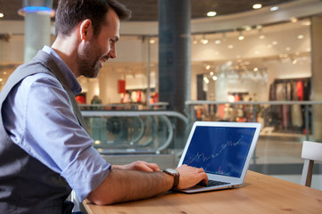 Investor analyzing stock market with charts on screen at restaurant