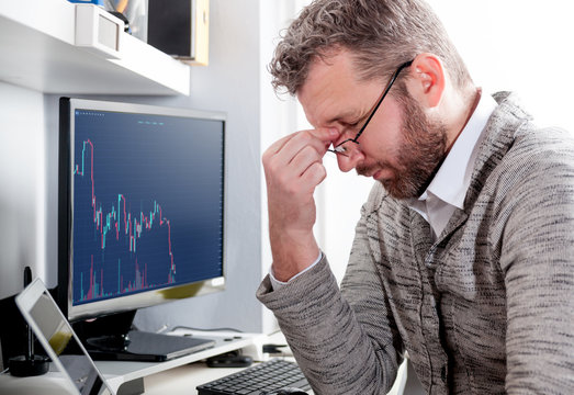 Depressed investor analyzing crisis stock market with graph on screen at home office