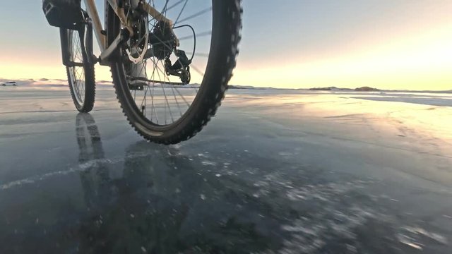 View of the tire. Shooting 60fps actioncam. Woman is riding bicycle on the ice. Ice of the frozen Lake Baikal. The tires on the bicycle are covered with special spikes. The traveler is ride a cycle.