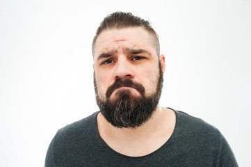 Obraz premium Portrait of young sad unhappy man with grey t-shirt looking at camera. studio shot, isolated on white background.