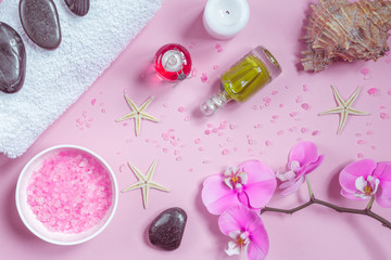 Spa background, flat lay layout with pink sea salt, candles and aroma oils and cosmetic care products on a pink background