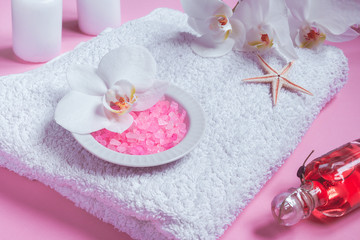 Fototapeta na wymiar Spa background, flat lay layout with pink sea salt, candles and aroma oils and cosmetic care products on a pink background