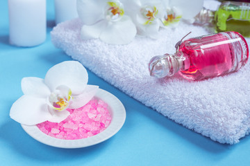 Spa background, flat layout with pink sea salt, candles and aroma oils and beauty care products on a blue background