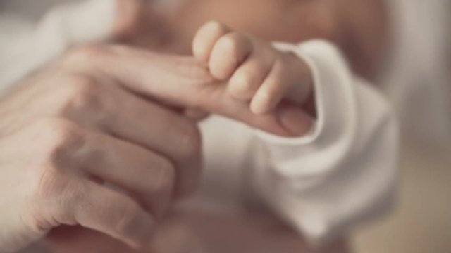 Young mother holding newborns hand. Close up in slow motion. Family concept