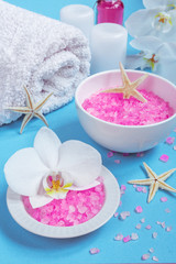 Obraz na płótnie Canvas Spa background, flat layout with pink sea salt, candles and aroma oils and beauty care products on a blue background